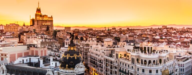 Imagem aérea da Gran Vía em Madrid, com destaque para os edifícios históricos e o movimento urbano