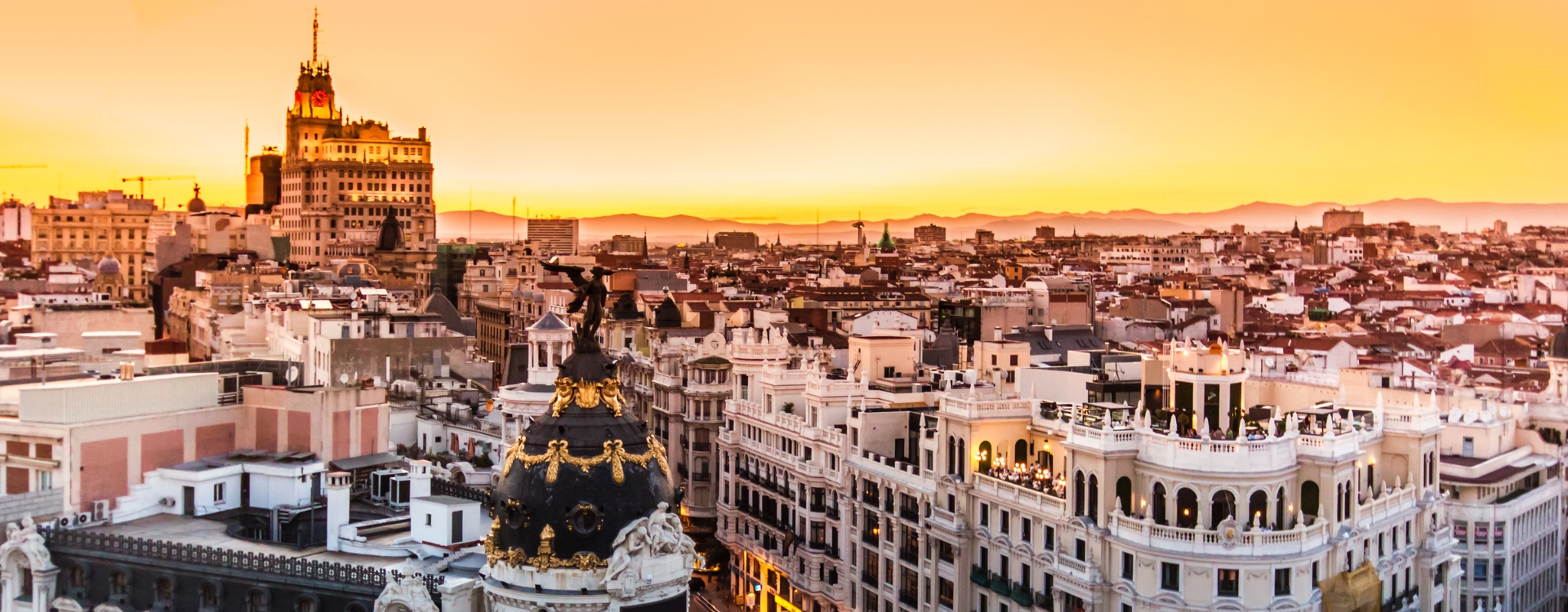 Imagem aérea da Gran Vía em Madrid, com destaque para os edifícios históricos e o movimento urbano